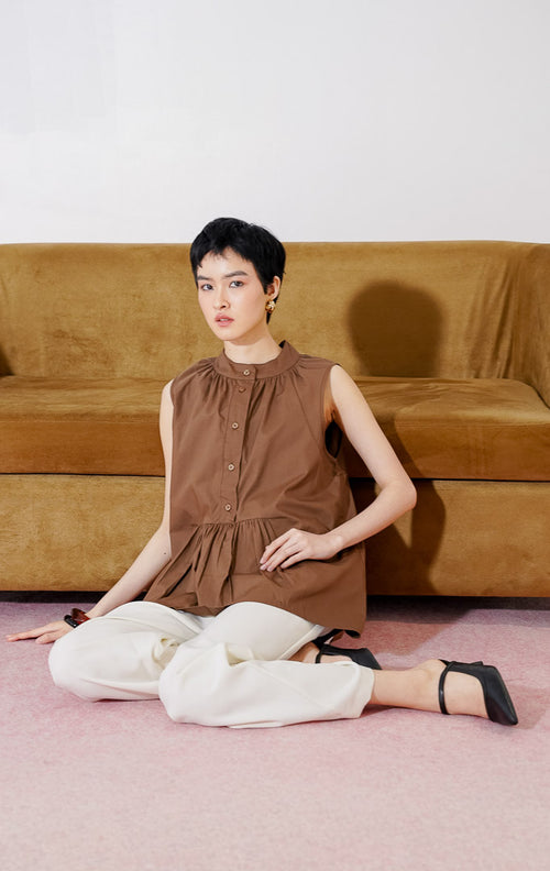 Atasan wanita tanpa lengan This Is April Lirien Top warna Dark Brown, dilengkapi kerah shanghai, kancing depan, dan siluet peplum longgar.