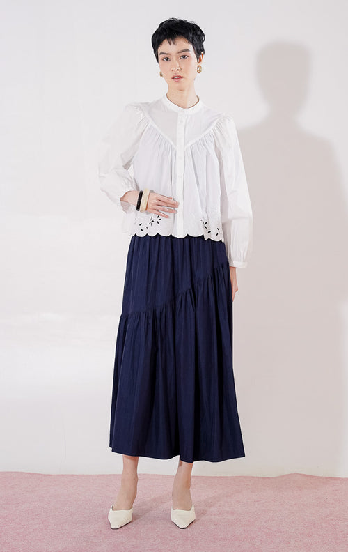 Blouse crop lengan panjang wanita This Is April Marvie Top warna putih berbahan katun, dengan kerah shanghai, kancing depan, jahitan yoke di dada, dan detail bordir bunga pada ujung bawah