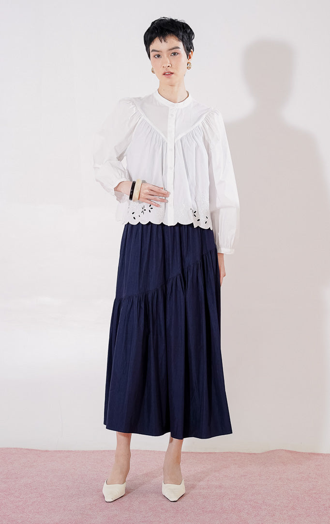 Blouse crop lengan panjang wanita This Is April Marvie Top warna putih berbahan katun, dengan kerah shanghai, kancing depan, jahitan yoke di dada, dan detail bordir bunga pada ujung bawah