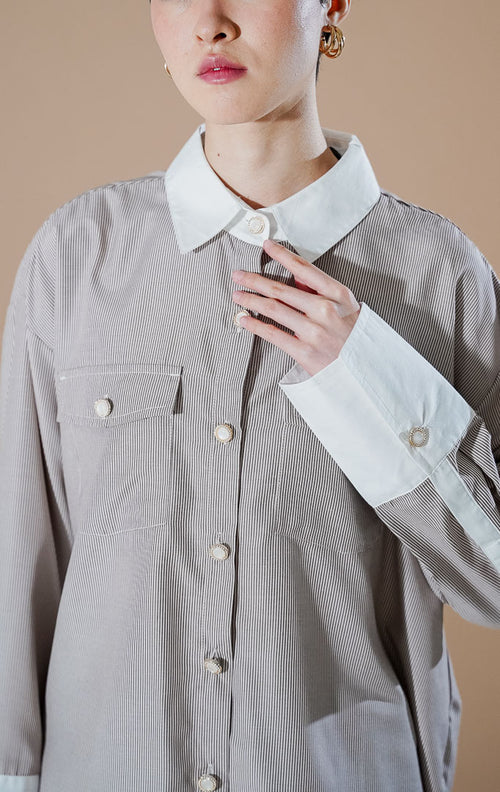 Merveille Top Brown Stripe dari This Is April, kemeja lengan panjang wanita motif garis cokelat putih dengan kerah dan ujung lengan warna putih kontras serta dua saku depan.