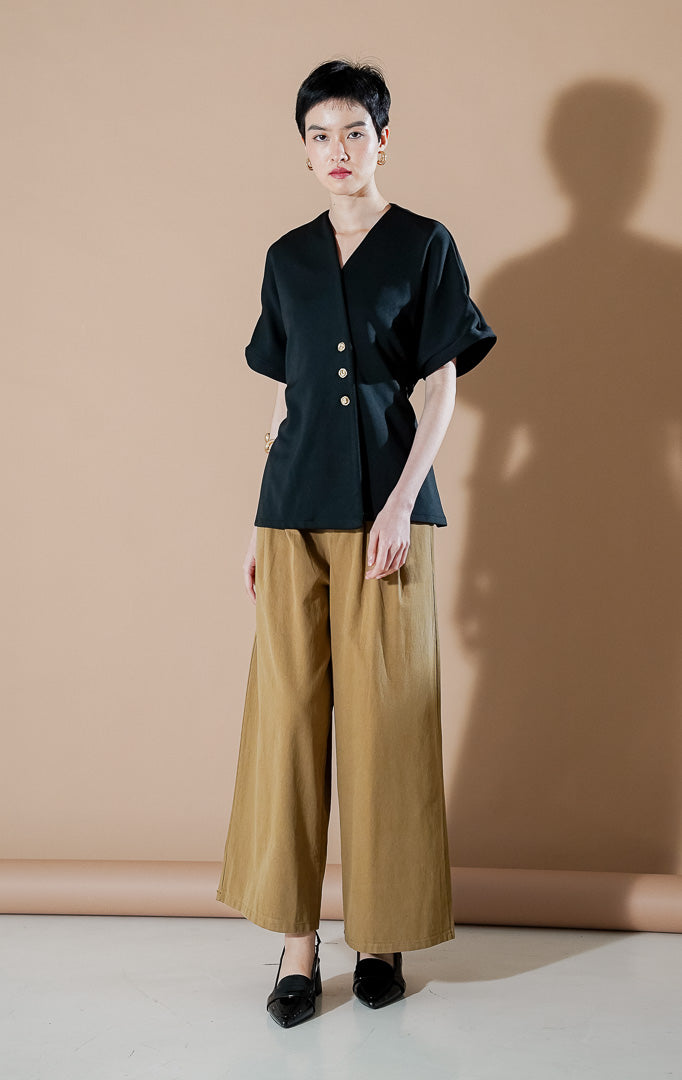 Moiselle Top Black dari This Is April, atasan lengan pendek wanita warna hitam dengan kerah V-neck, detail kancing emas di bagian samping, dan siluet terstruktur.