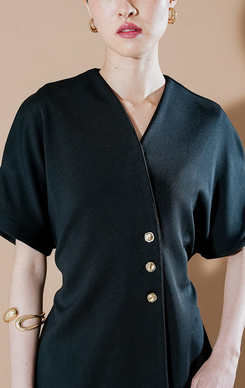 Moiselle Top Black dari This Is April, atasan lengan pendek wanita warna hitam dengan kerah V-neck, detail kancing emas di bagian samping, dan siluet terstruktur.
