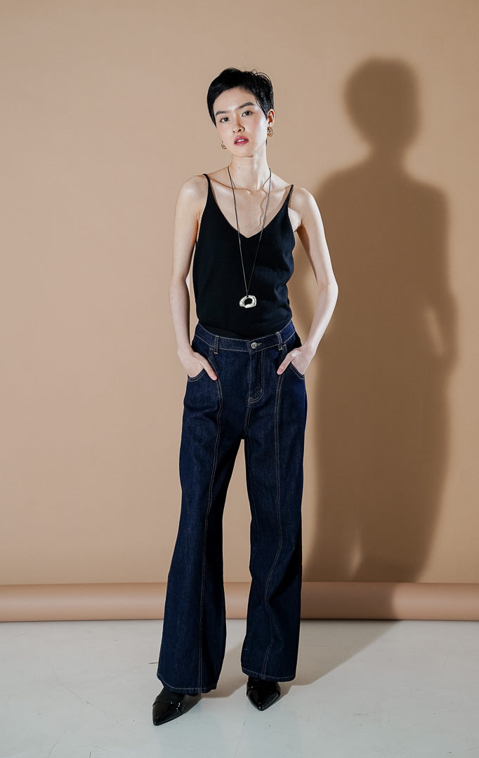 Nadette Pants Indigo dari This Is April, celana jeans wanita warna biru indigo tua dengan detail jahitan cokelat kontras di bagian depan dan siluet kaki lebar.