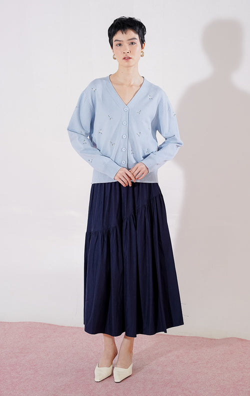 Tampak depan This Is April Petunia Cardigan warna [isi dengan biru/abu-abu], berupa cardigan rajut lengan panjang kerah V-neck dengan kancing depan dan detail motif bordir bunga kecil yang tersebar. 