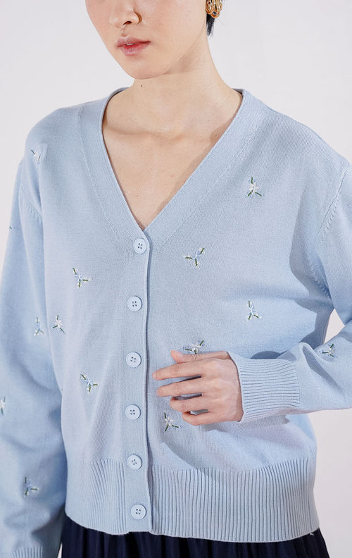 Tampak depan This Is April Petunia Cardigan warna [isi dengan biru/abu-abu], berupa cardigan rajut lengan panjang kerah V-neck dengan kancing depan dan detail motif bordir bunga kecil yang tersebar. 