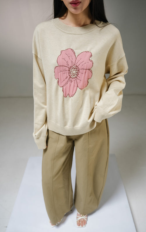 Atasan sweater rajut lengan panjang wanita This Is April Samantha Sweater warna cream, model kerah bulat dengan detail motif grafis bunga besar warna pink di bagian tengah depan. 