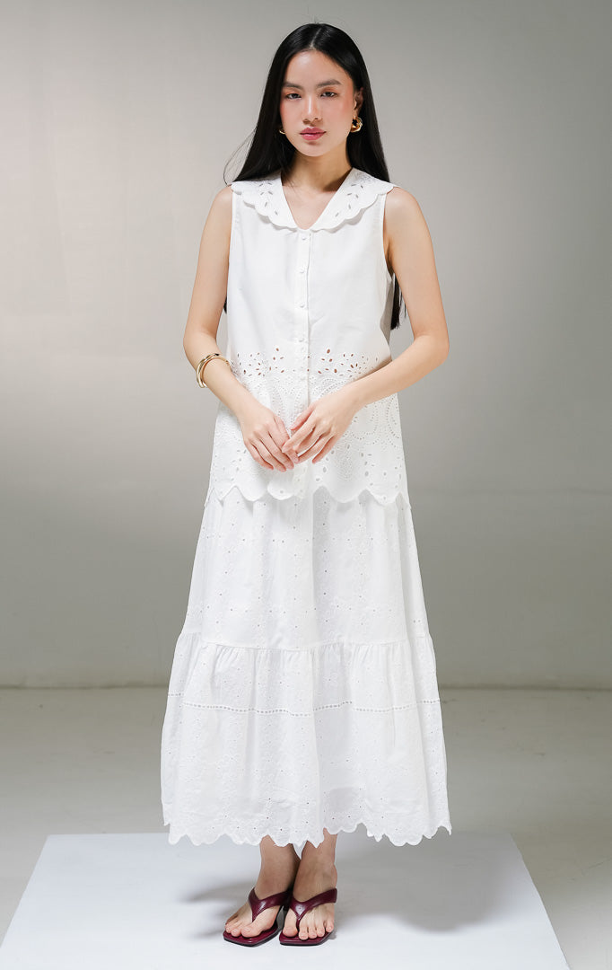Atasan blouse tanpa lengan wanita This Is April Therine Top warna putih, model sleeveless shirt dengan kerah v-neck lebar bergelombang scalloped dan detail bordir bolong katbol di bagian bawah. 