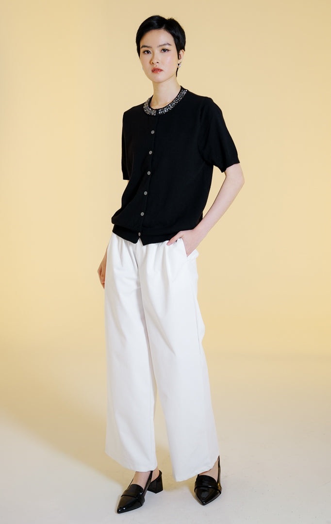 Pakaian wanita model atasan rajut cardigan lengan pendek dengan kancing depan dan hiasan permata di bagian kerah bulat (gemstone neckline short sleeve knit top) warna hitam Alveria Top untuk gaya kantor dan kasual anggun. 