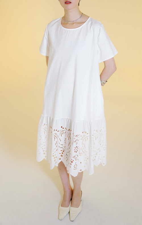 Pakaian wanita model gaun midi lengan pendek dengan detail bordir lubang bunga di bagian bawah (floral eyelet embroidered midi dress) warna putih Corrine Dress untuk gaya kasual anggun.