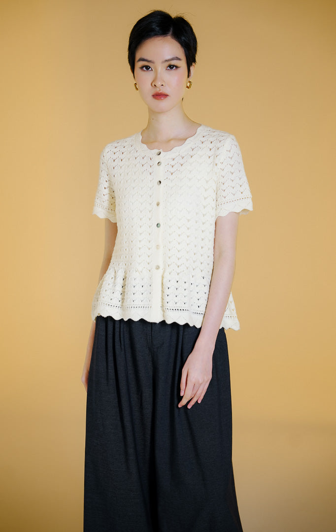 Pakaian wanita model atasan rajut cardigan lengan pendek kancing depan dengan motif kerawang crochet (pointelle crochet knit top) warna gading Cyralis Top untuk gaya kasual anggun.