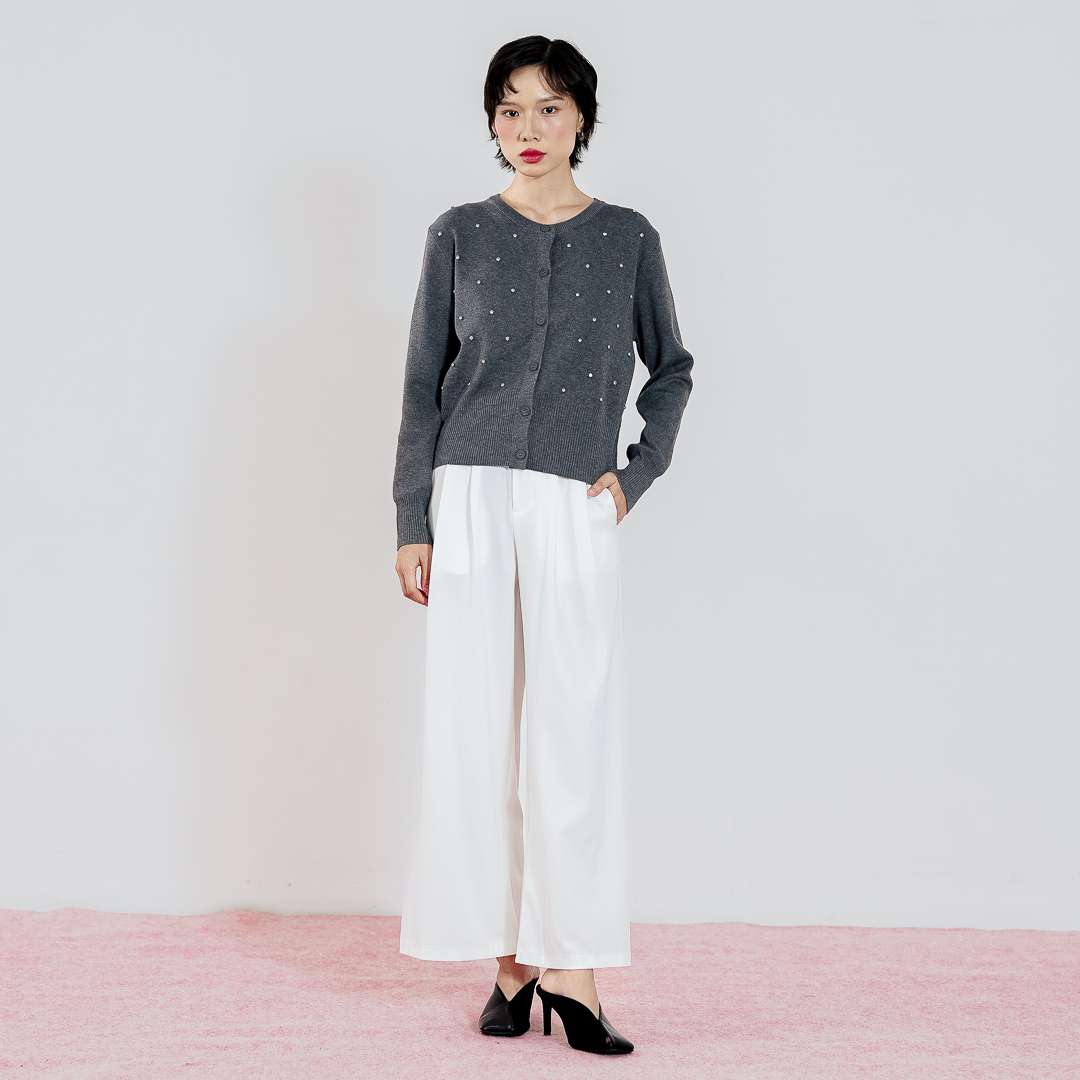 Model mengenakan This Is April Daimen Cardigan Grey, knit cardigan abu-abu dengan detail manik-manik rhinestone dan celana putih.