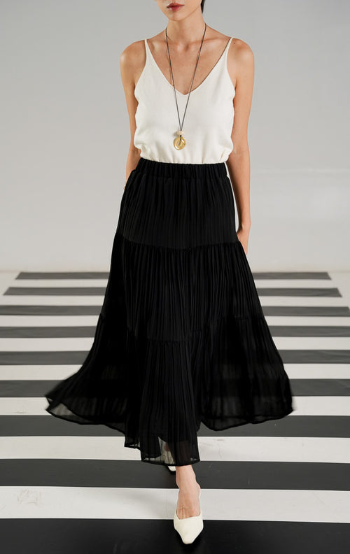 Rok panjang (maxi skirt) wanita warna hitam (black) dengan detail lipit (pleated), potongan bersusun atau berundak (tiered), dan karet pinggang elastis dari This Is April. 