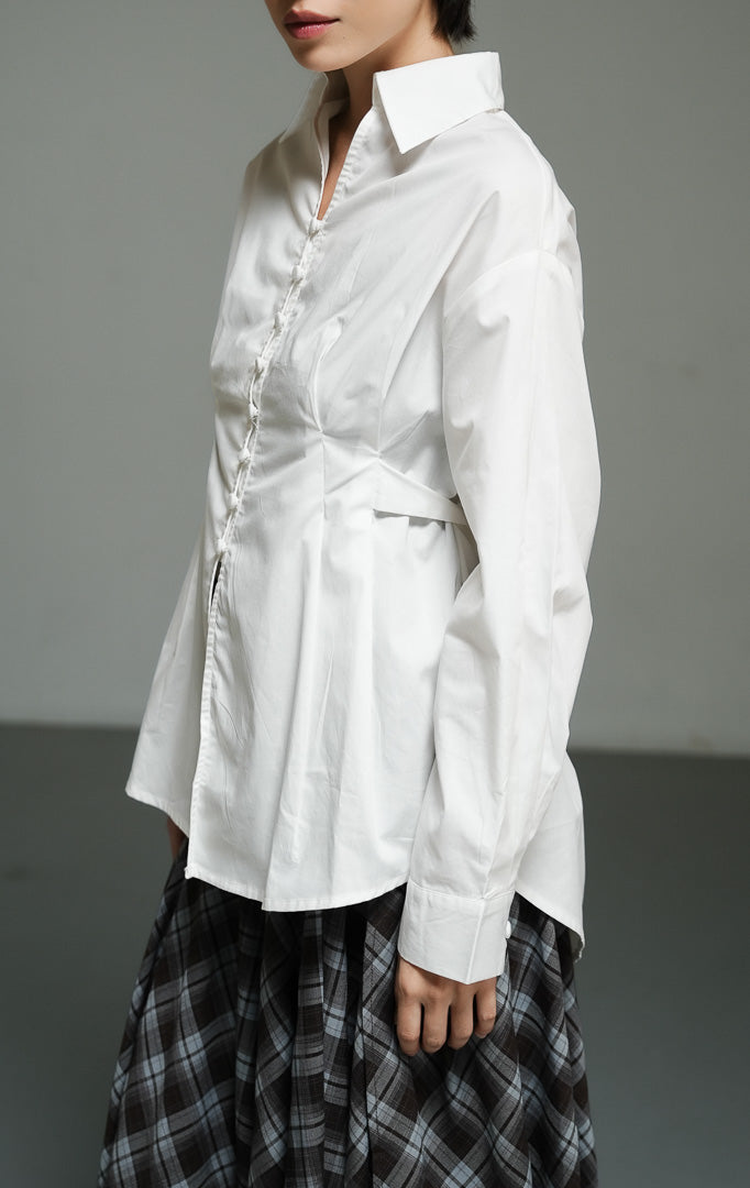 Atasan wanita model kemeja katun lengan panjang warna putih (white corseted waist shirt top) Effie Top dengan detail siluet korset pada bagian pinggang yang membentuk lekuk tubuh proporsional. 

