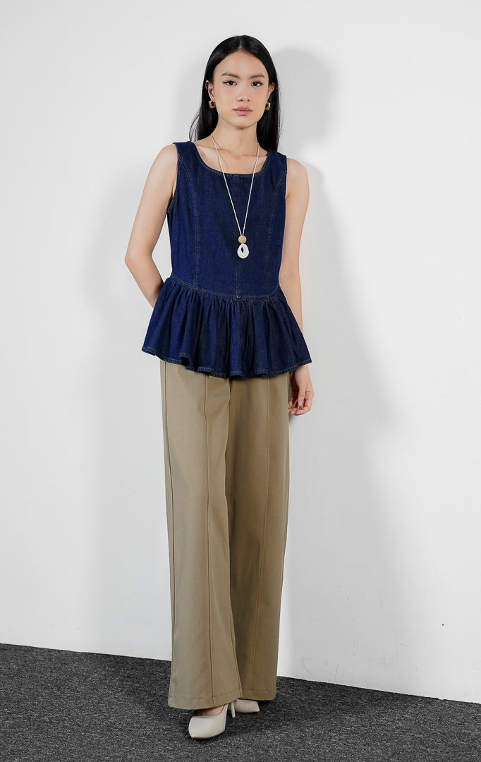 Atasan wanita model peplum tanpa lengan bahan denim warna dark denim dengan potongan pinggang rendah yang terstruktur (dark denim sculpted drop-waist peplum top) Emalyne Top untuk gaya feminin modern.