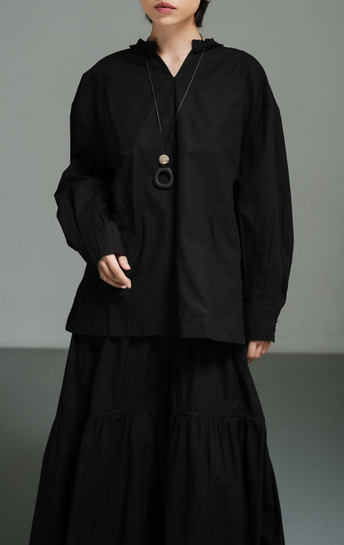 Blus wanita lengan panjang warna hitam (black pleated-trim stand collar blouse) Florina Top dengan bahan katun poplin berkualitas, kerah tegak berdetail lipatan plisket, serta potongan siluet modern yang tegas. 