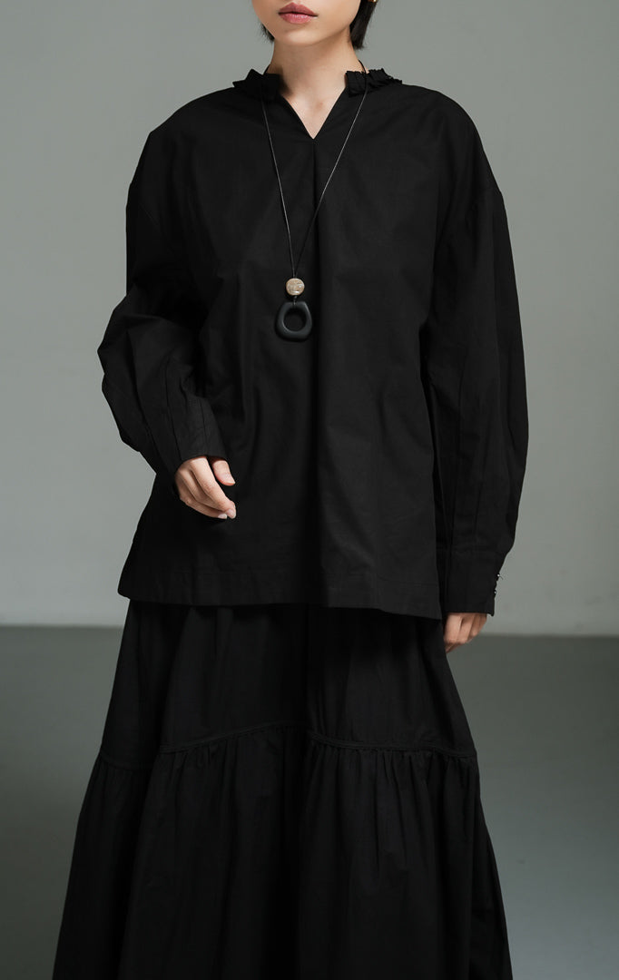 Blus wanita lengan panjang warna hitam (black pleated-trim stand collar blouse) Florina Top dengan bahan katun poplin berkualitas, kerah tegak berdetail lipatan plisket, serta potongan siluet modern yang tegas. 