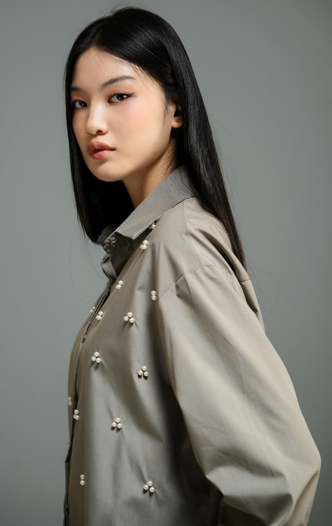 Kemeja wanita lengan panjang warna hijau olive (olive beaded button-down shirt) Freesia Top dengan detail hiasan manik-manik mutiara bentuk klaster bunga di bagian depan, kerah klasik, serta kancing penuh. 