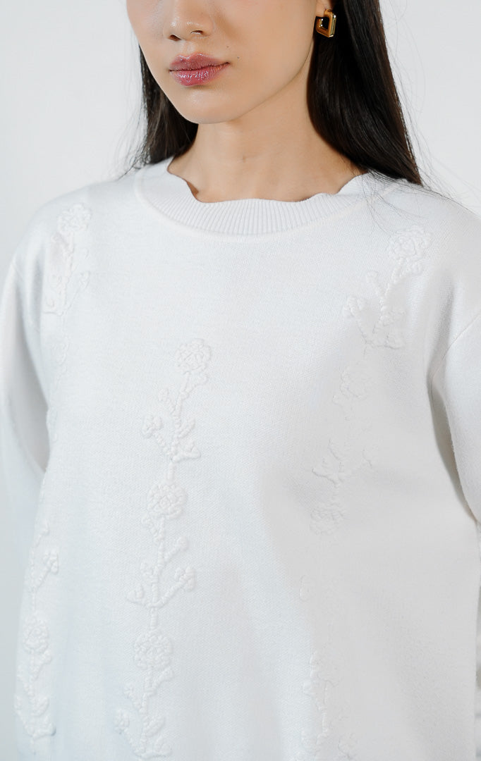 Atasan wanita model sweater rajut lengan panjang warna putih dengan detail hiasan bunga rajut dan potongan bawah bergelombang (white crochet flower scallop knit sweater) Galina Sweater untuk gaya kasual yang anggun.