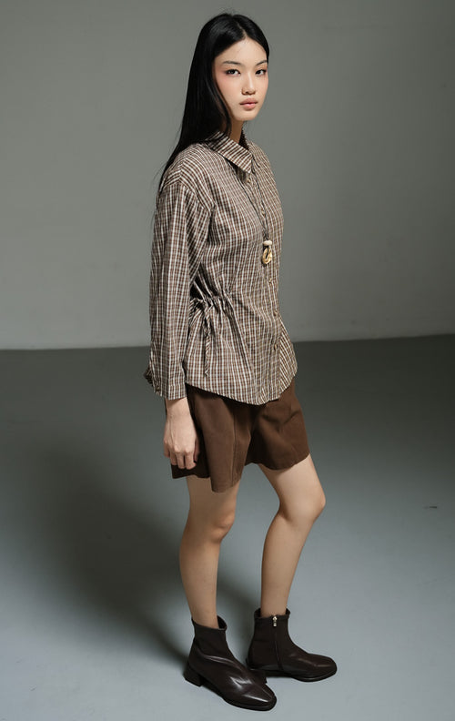 Kemeja wanita lengan panjang motif kotak-kotak warna cokelat (brown plaid drawstring shirt top) Hilaria Top dengan bahan katun non-stretch berkualitas, penutup kancing depan, serta tali serut pinggang untuk siluet yang ramping dan rapi. 
