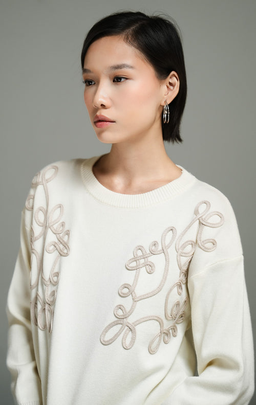 Atasan wanita model sweater rajut warna ivory dengan detail bordir tali bermotif bunga (ivory floral cord embroidery knit sweater) Jenny Sweater untuk tampilan kasual yang anggun. 