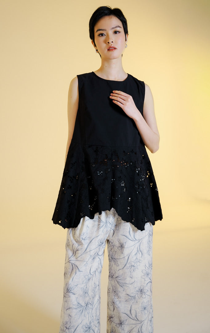 Pakaian wanita model atasan tanpa lengan bahan katun dengan potongan peplum dan bordir lubang bunga serta bagian bawah zig-zag (floral eyelet peplum sleeveless top) warna hitam Kareth Top untuk gaya kasual anggun.