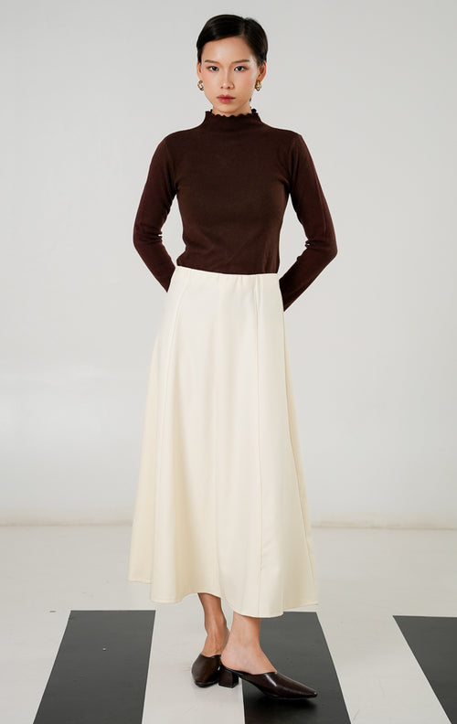 Rok midi wanita (midi skirt) warna cream (krem) berpotongan rapi dengan detail jahitan panel lurus dan resleting (zipper) tersembunyi dari This Is April. 