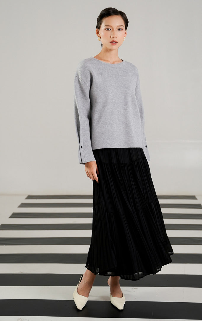 Atasan rajut wanita lengan panjang warna abu abu (grey) dengan kerah bulat dan detail deretan kancing kecil berwarna hitam di bagian tengah dari This Is April. 