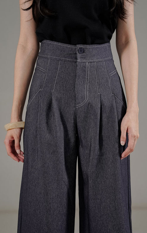 Marcela Pants Navy dari This Is April, celana panjang highwaist warna biru dongker dengan detail dua kancing depan dan saku samping.