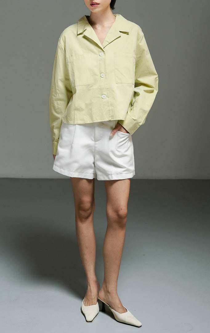 Atasan wanita model blazer pendek (cropped blazer top) warna hijau sage (green Cuban collar cropped blazer) Meadow Top dengan detail kerah Kuba, bahan katun berstruktur non-stretch, serta kancing depan penuh.