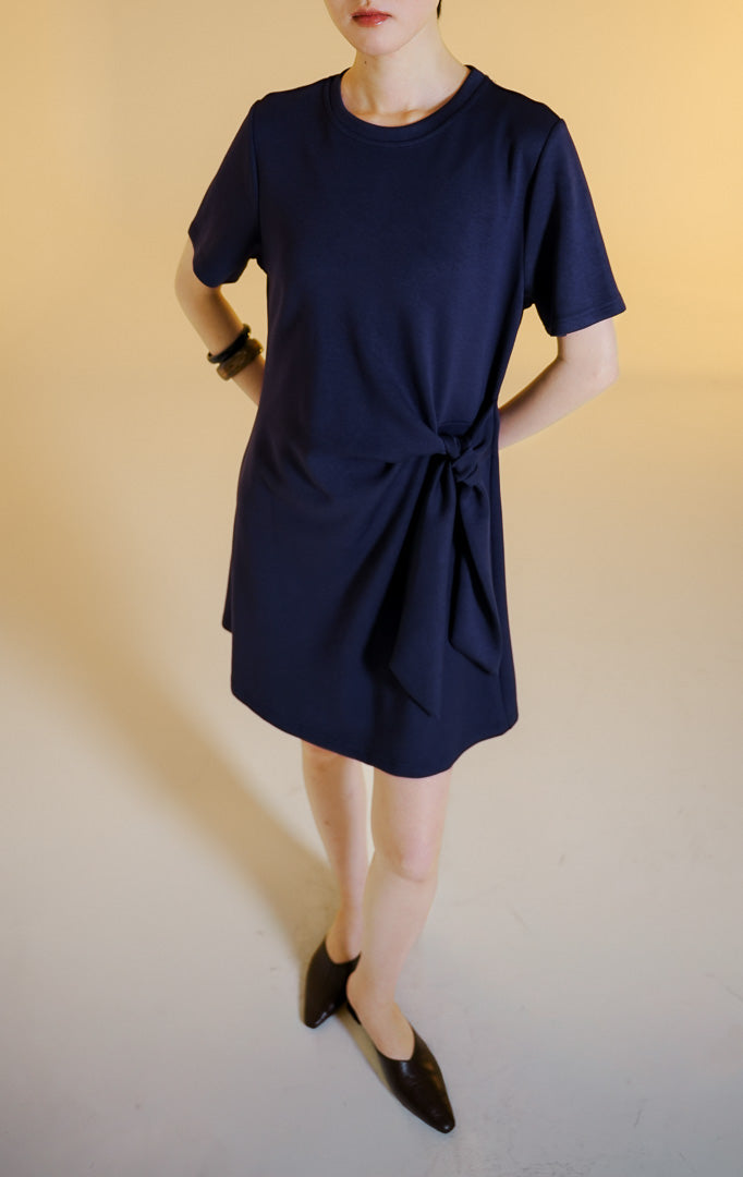Pakaian wanita model gaun pendek terusan lengan pendek berkerah bulat dengan aksen simpul ikatan di samping (side-knot scuba mini dress) warna navy Merily Dress untuk gaya kantor dan kasual anggun. 