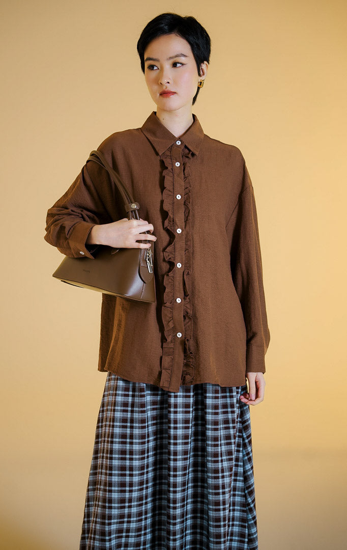 Pakaian wanita model kemeja lengan panjang berkerah dengan detail kerutan rempel di sepanjang kancing depan (dual-sided ruffled placket shirt) warna cokelat tua Mirena Top untuk gaya kantor dan kasual anggun.