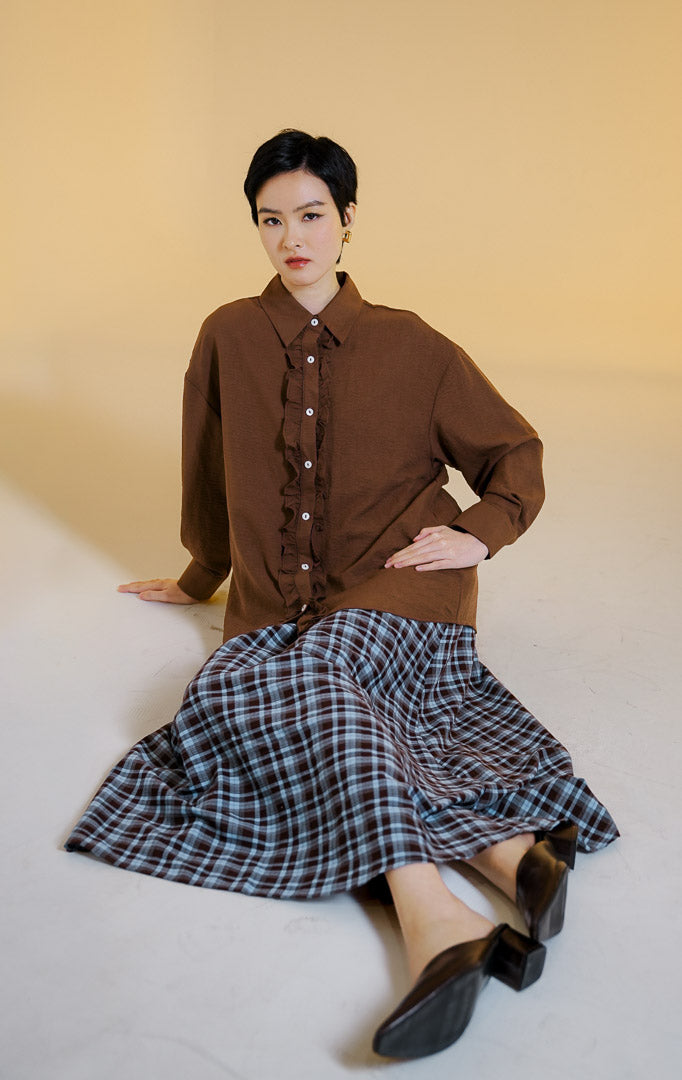 Pakaian wanita model kemeja lengan panjang berkerah dengan detail kerutan rempel di sepanjang kancing depan (dual-sided ruffled placket shirt) warna cokelat tua Mirena Top untuk gaya kantor dan kasual anggun.