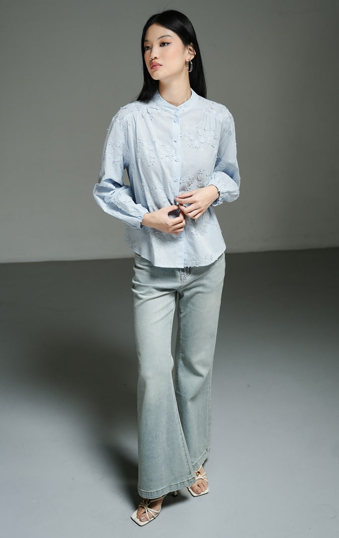 Blus wanita lengan panjang warna biru muda (light blue leaf embroidered cotton blouse) Nerine Top dengan detail sulam motif daun yang cantik, bahan katun non-stretch berstruktur, serta kancing depan yang rapi. 
