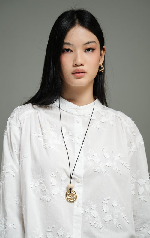 Blus wanita lengan panjang warna putih (white leaf embroidered cotton blouse) Nerine Top dengan detail bordir daun yang halus, bahan katun berkualitas non-stretch yang berstruktur, serta kancing depan klasik.