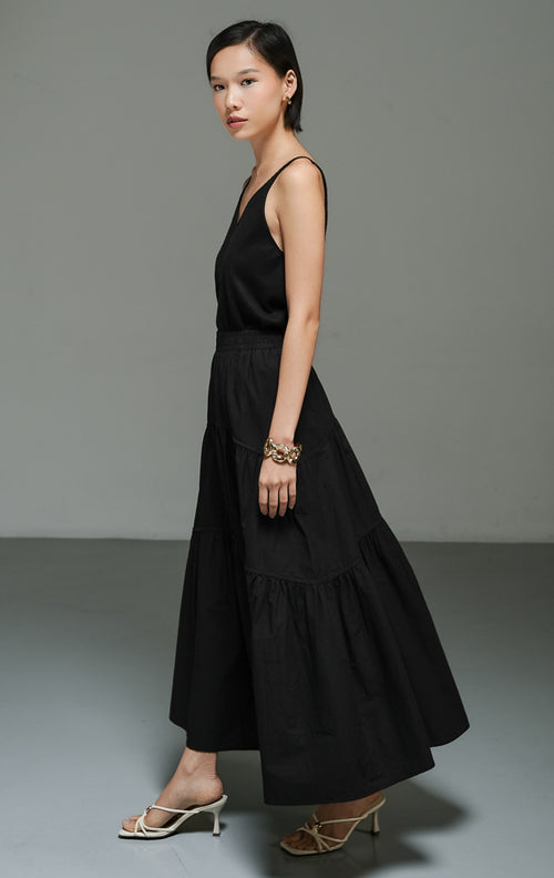 Rok panjang wanita model maxi flared warna hitam (black gathered flared maxi skirt) Okeanos Skirt dengan detail kerut bertingkat, bahan yang jatuh dengan lembut, serta tampilan elegan yang serbaguna. 

