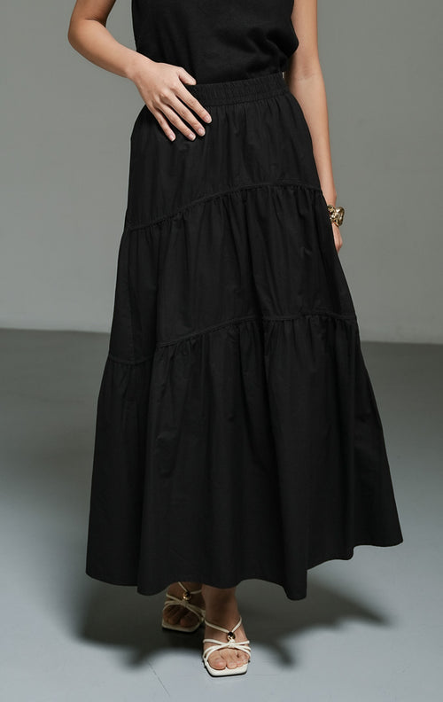 Rok panjang wanita model maxi flared warna hitam (black gathered flared maxi skirt) Okeanos Skirt dengan detail kerut bertingkat, bahan yang jatuh dengan lembut, serta tampilan elegan yang serbaguna. 