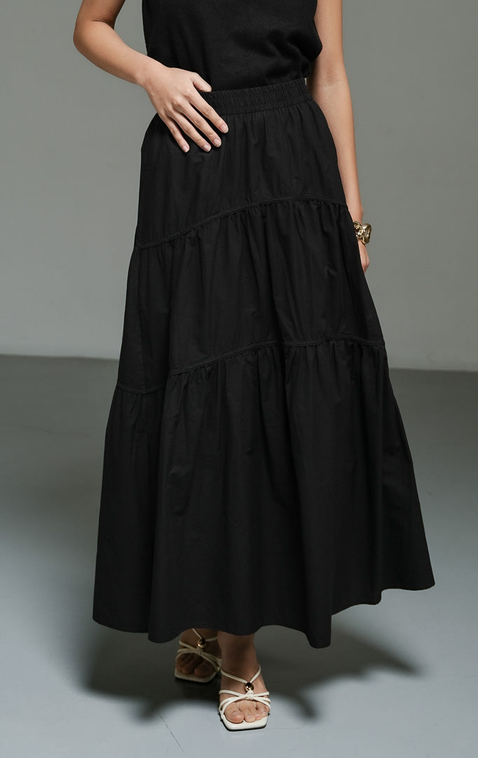 Rok panjang wanita model maxi flared warna hitam (black gathered flared maxi skirt) Okeanos Skirt dengan detail kerut bertingkat, bahan yang jatuh dengan lembut, serta tampilan elegan yang serbaguna. 