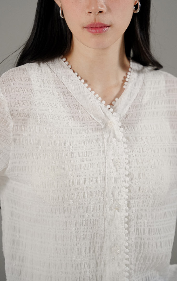 Palmer Top White dari This Is April, blus lengan panjang wanita warna putih bahan sheer transparan dengan detail bordir benang timbul dan kerah V.