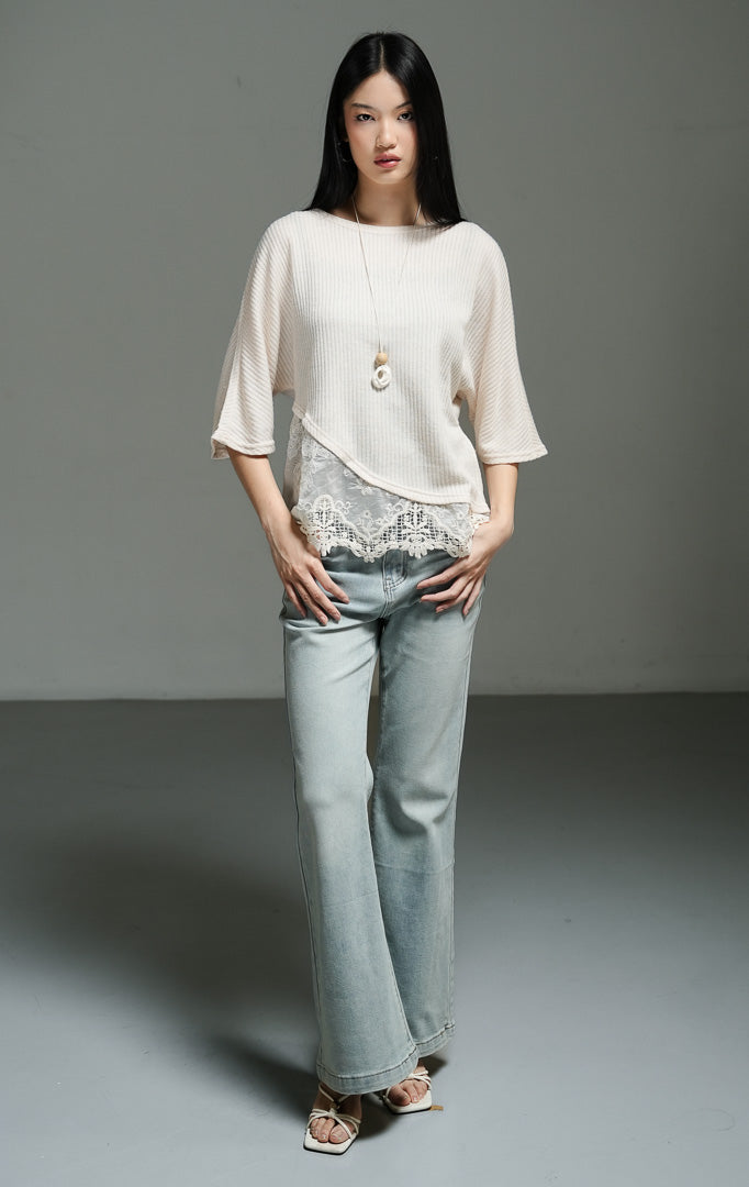 Atasan wanita model rajut oversize lengan setengah warna ivory dengan detail asimetris dan lapisan renda pada bagian bawah (ivory oversized knit top with lace overlay) Rachelle Top yang anggun dan chic. 