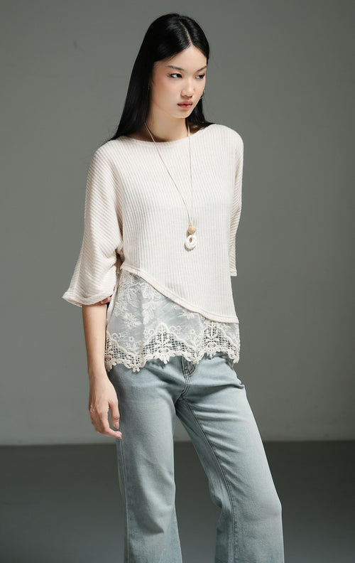 Atasan wanita model rajut oversize lengan setengah warna ivory dengan detail asimetris dan lapisan renda pada bagian bawah (ivory oversized knit top with lace overlay) Rachelle Top yang anggun dan chic. 

