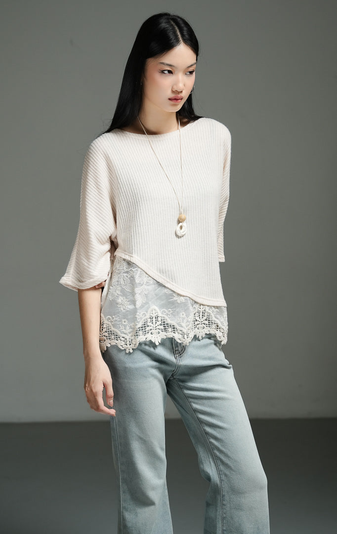 Atasan wanita model rajut oversize lengan setengah warna ivory dengan detail asimetris dan lapisan renda pada bagian bawah (ivory oversized knit top with lace overlay) Rachelle Top yang anggun dan chic. 

