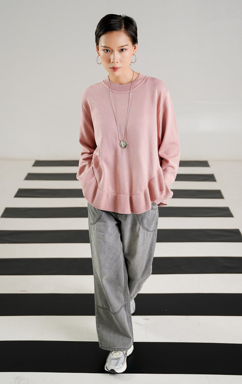 Sweater rajut wanita lengan panjang warna merah muda (pink) dengan detail hem ruffle bergelombang di bagian bawah dari This Is April. 
