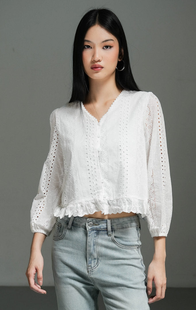 Blus wanita lengan panjang warna putih (white broderie anglaise eyelet blouse) Rexana Top dengan detail lubang sulam dekoratif, bahan katun yang ringan, serta siluet modern bergaya vintage. 