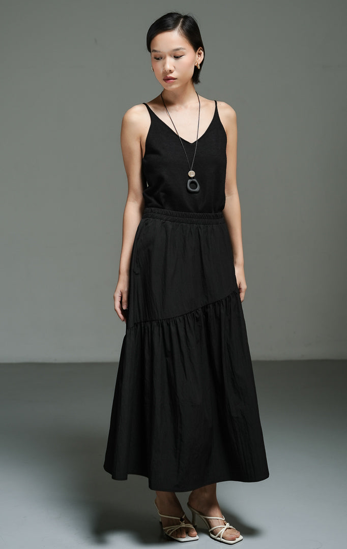 Rok panjang wanita model maxi asimetris warna hitam (black asymmetric gathered maxi skirt) Riami Skirt dengan desain potongan miring yang modern, detail kerut bertingkat yang anggun, serta siluet kasual berkelas. 
