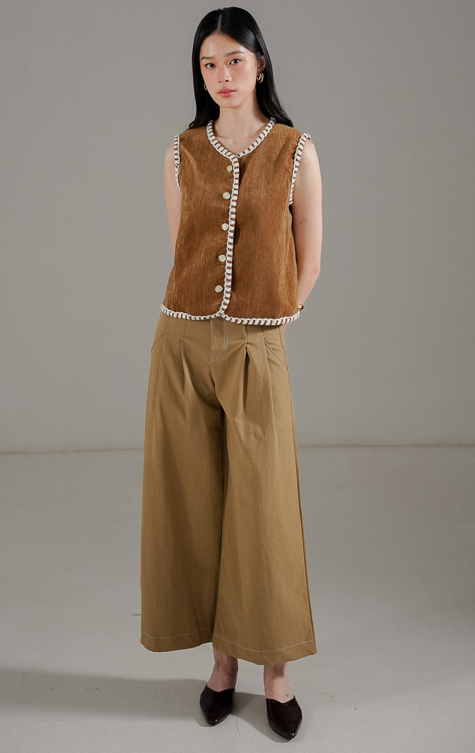 Vesta Vest Brown dari This Is April, rompi tanpa lengan warna cokelat mustard dengan detail jahitan tepi warna putih dan kancing emas.