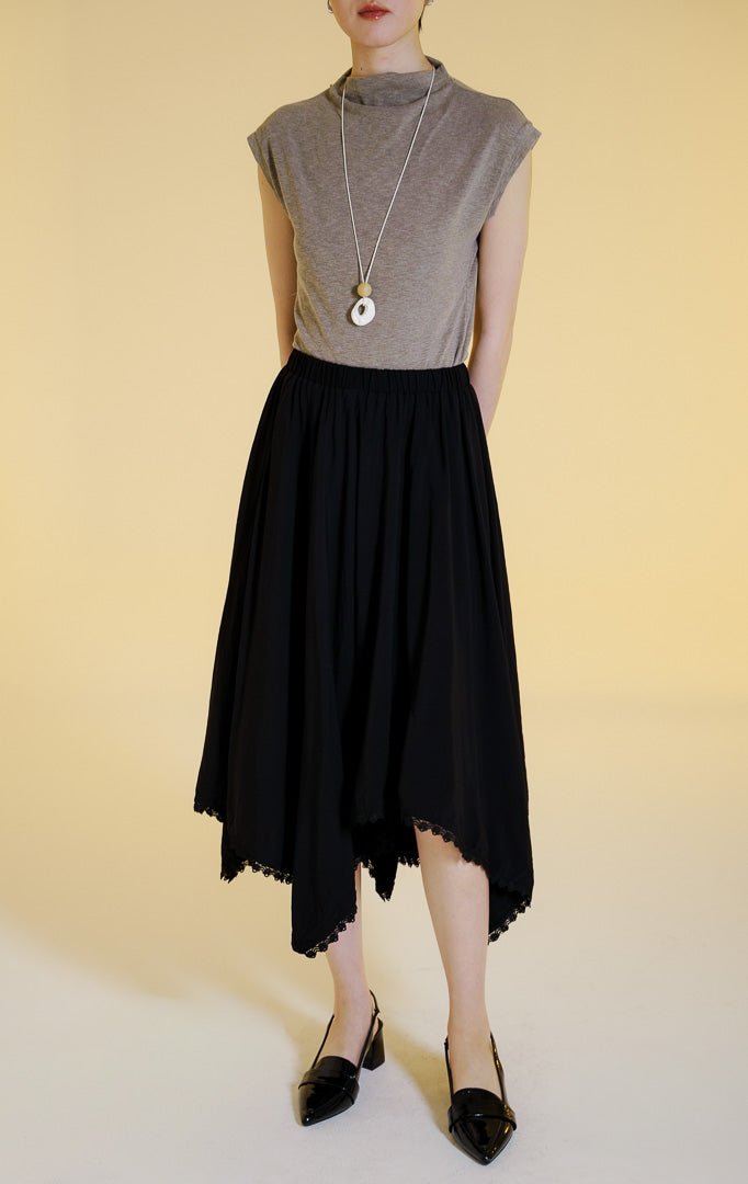 Pakaian wanita model rok panjang maxi dengan pinggang karet dan potongan bawah asimetris dilapisi renda (uneven lace trim flowy maxi skirt) warna hitam Villera Skirt untuk gaya kantor dan kasual anggun. 