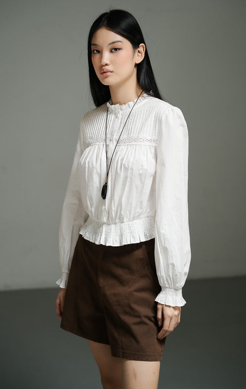 Atasan wanita model blus peplum lengan panjang warna putih (white pin-tucked peplum blouse) Violetta Top dengan detail lipatan pin-tuck yang bertekstur serta potongan pinggang yang anggun. 