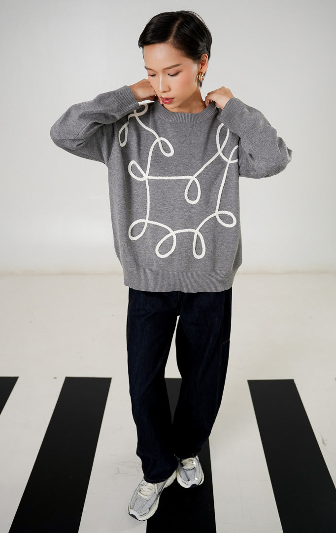 Sweater rajut wanita lengan panjang warna abu abu (grey) dengan detail bordir garis lengkung abstrak berwarna putih di bagian depan dari This Is April. 