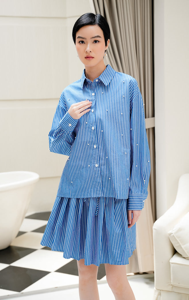 Kemeja lengan panjang wanita Tigris Top warna dark blue (biru tua) motif stripe (salur) dengan hiasan mutiara (pearl embellishments) dan kancing depan. 
