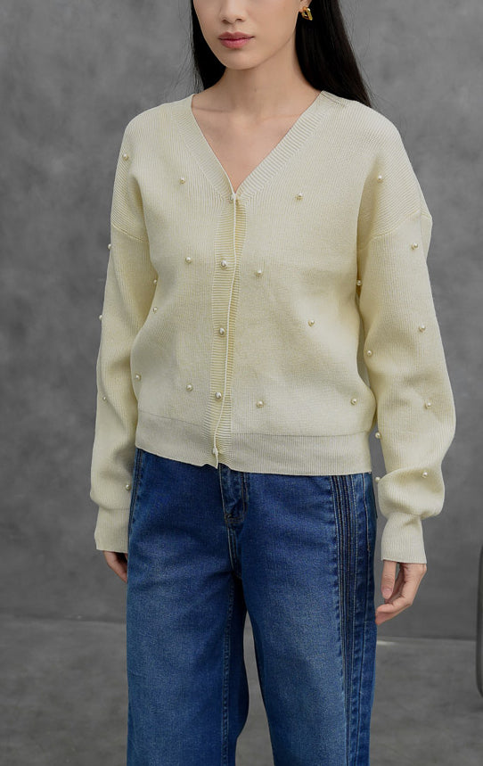 Kardigan rajut wanita lengan panjang warna ivory Vanessa Cardigan dengan kerah V (V-neck), bukaan kancing depan, dan aksen hiasan mutiara (scattered pearl details).